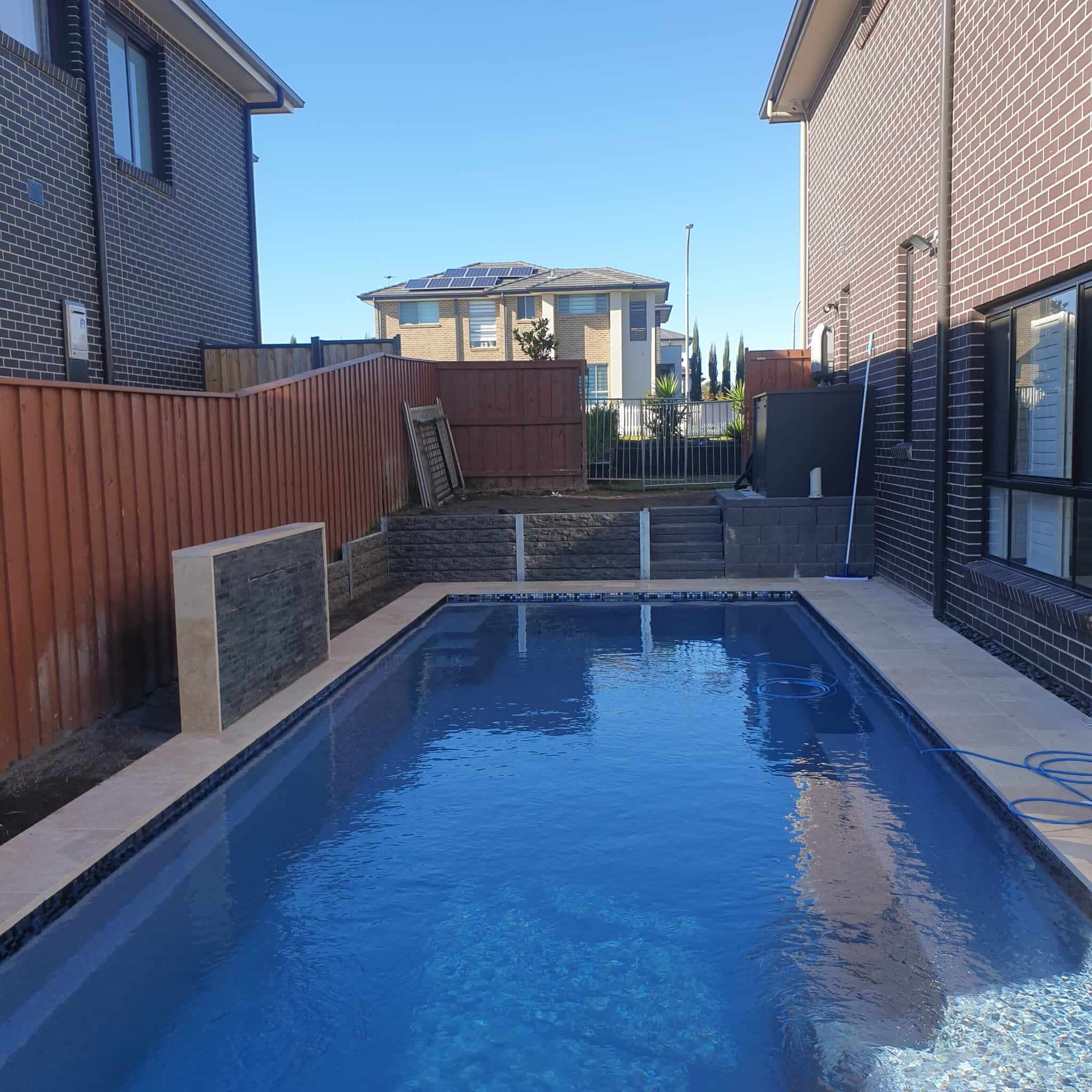 Swimming pool with a paved surround and sleeper wall built by Active Landscapes