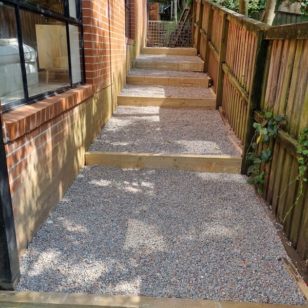 Gravel side path with timber sleeper steps beside a brick house