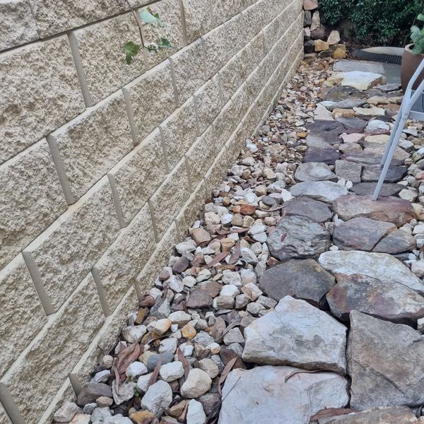 Block retaining wall with a rock-filled drainage bed alongside