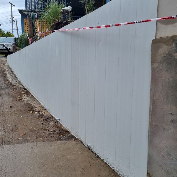 Rendered concrete retaining wall running the length of a driveway