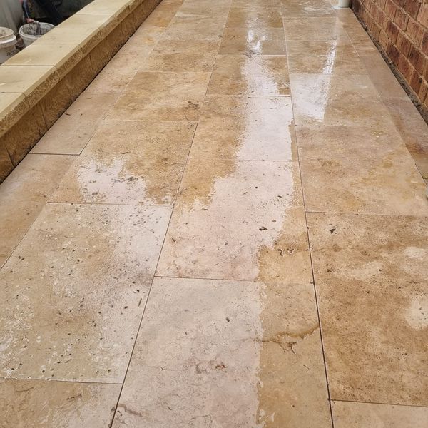 Travertine tiled path running alongside a brick wall