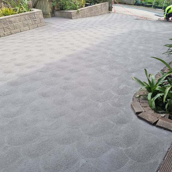 Concrete driveway framed by retaining walls and garden beds
