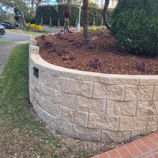 Curved block retaining wall along a street frontage with a mulched bed