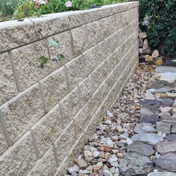 Block retaining wall with a rock drainage bed running along its base