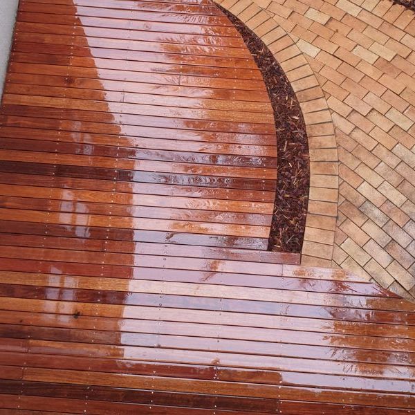 Curved hardwood deck meeting a brick paved surround