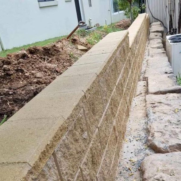 Sandstone block retaining wall with reinforcement bars still exposed