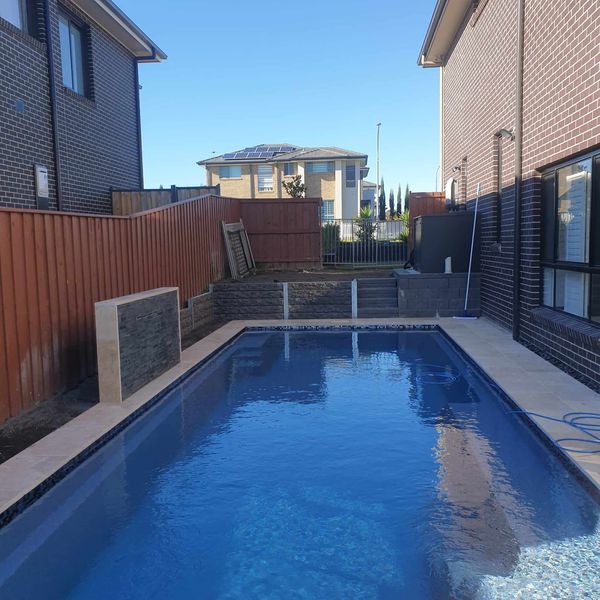 Swimming pool with a paved surround and timber sleeper wall behind