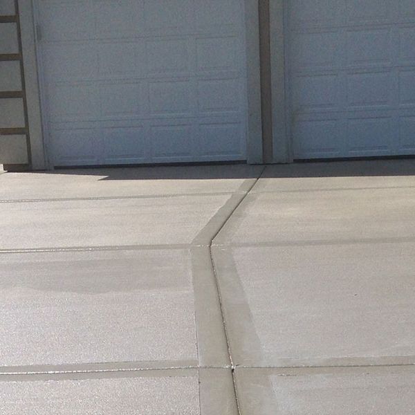 Finished concrete driveway running up to a double garage